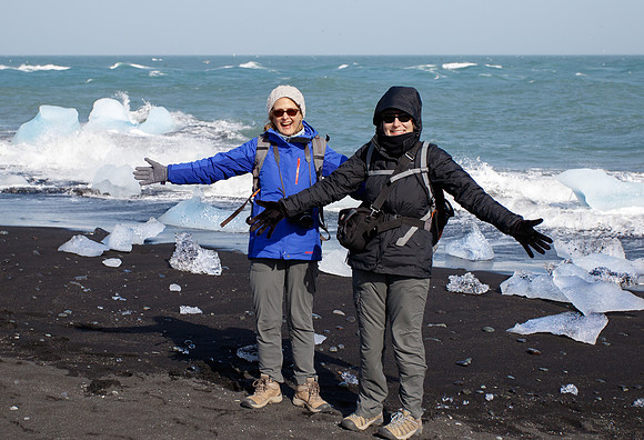 Drift ice flows into the ocean and washes up on black sand beach